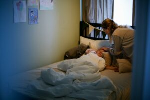 A mother caring for her sick child in a cozy bedroom setting, emphasizing love and comfort.