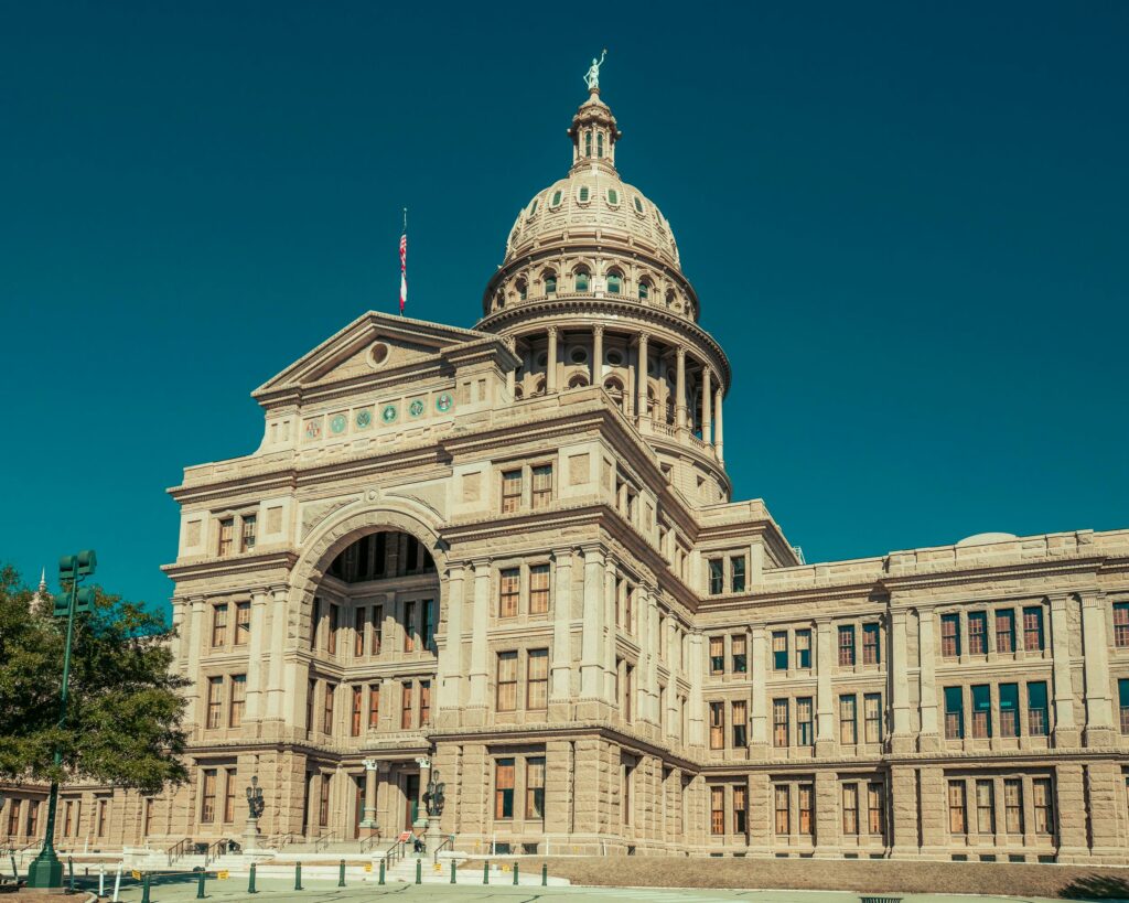 Low angle shot of the historical Texas State Capitol building under a clear blue sky in Austin, TX.